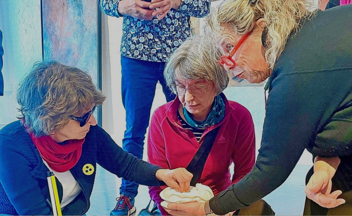 Künstlerin Ulrike Arnold hält Manuela Dolf und Gesine Wächter ein Ausstellungsstück hin, das sie ertasten konnten